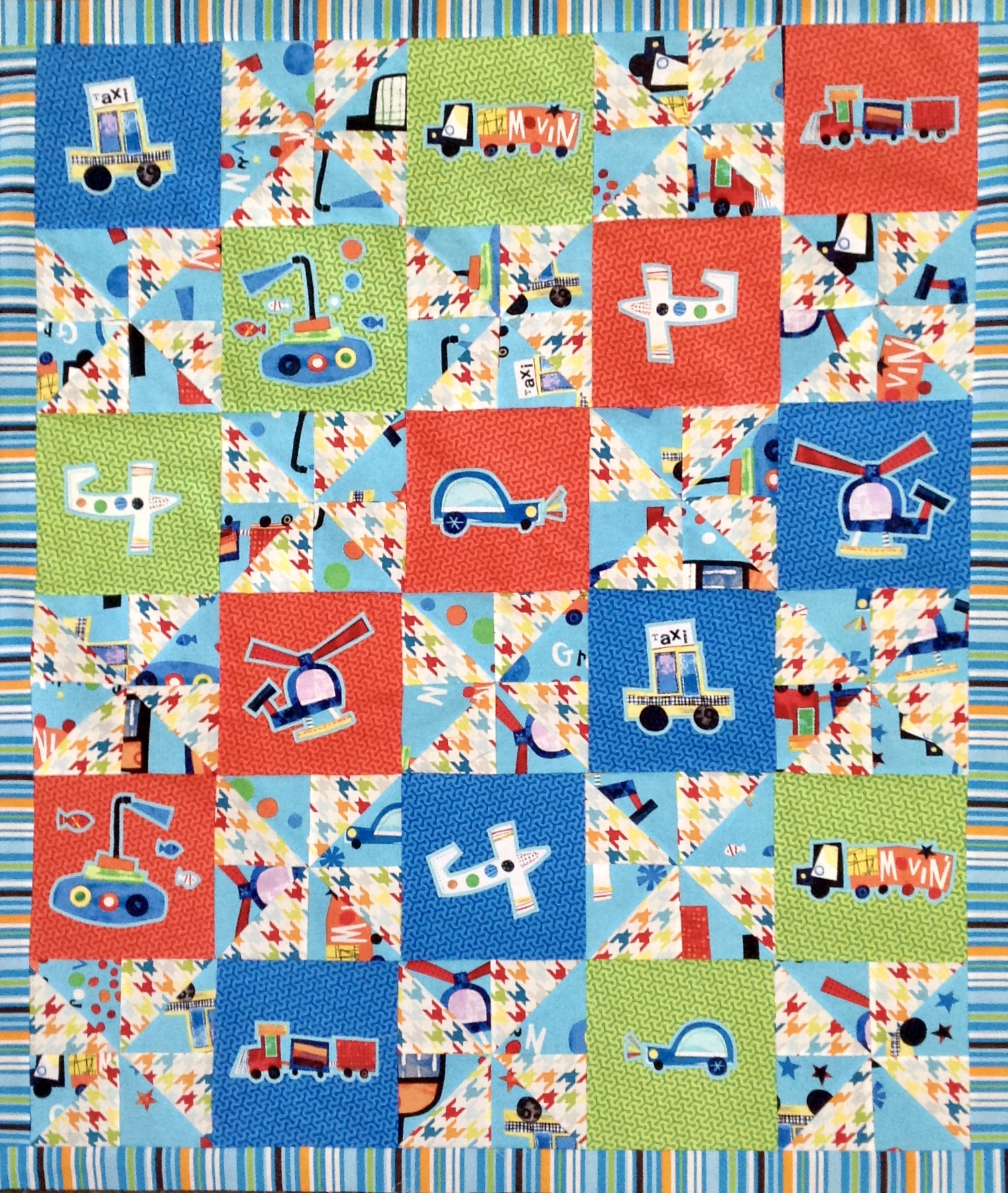 Red, blue, and green baby quilt with applique vehicles